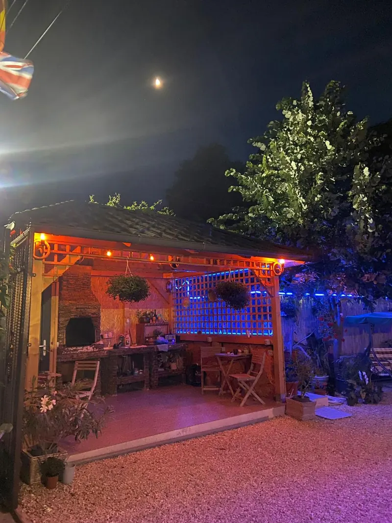 Foișorul de lemn cu grătar, luminat în portocaliu seara.