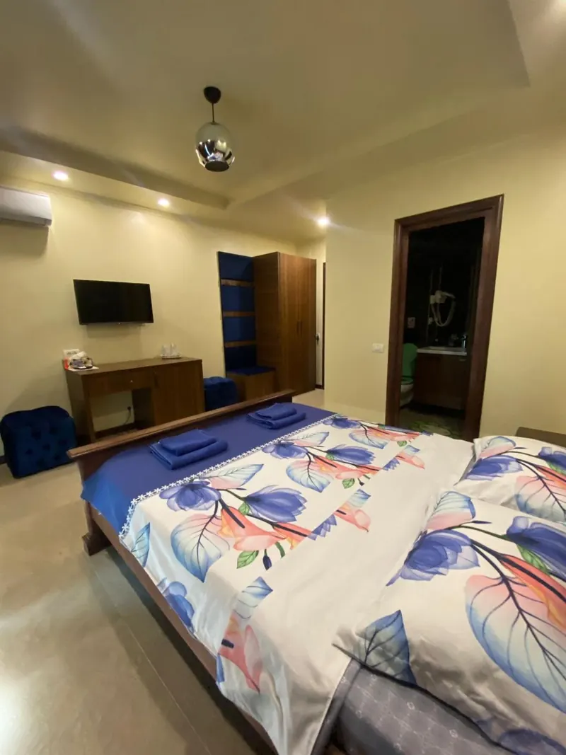 Cameră cu Smart TV, birou și ușa băii proprii deschisă.